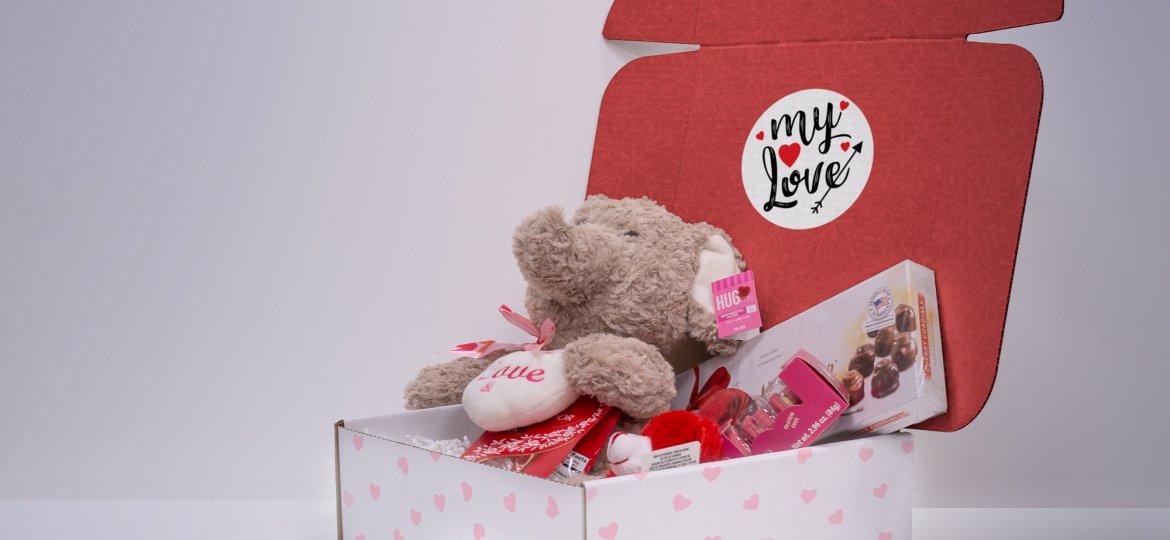 a valentines themed mailer box with the text "my love" on the inside flap, with stuffed animals and chocolates inside