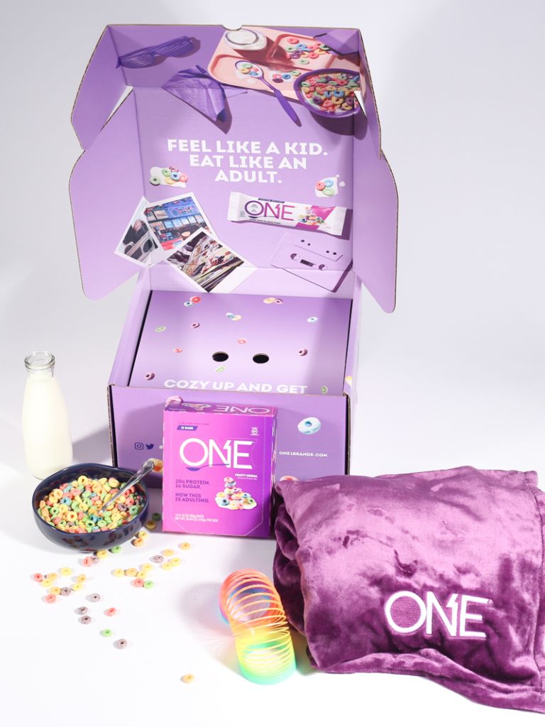 a purple blanket, slinky and bowl of cereal next to a purple box with the brand "One" bars on it